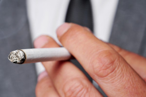 a man wearing a suit smoking a cigarette